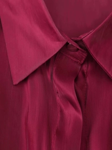Detail of burgundy satin shirt featuring lapel collar and matching fabric-covered buttons