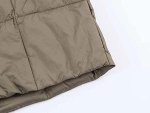 Close-up of olive green quilted puffer jacket fabric with square pattern stitching