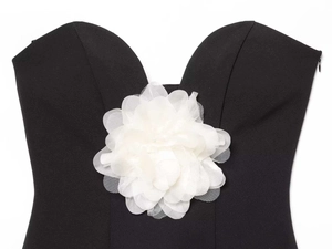 Gros plan d'une fleur 3D en maille blanche sur un haut tube noir avec fermeture invisible