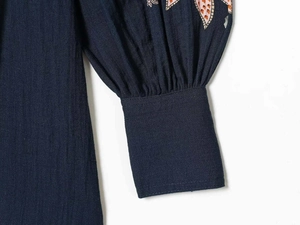 Detailed view of puff sleeves with navy geometric embroidery and textured cotton fabric