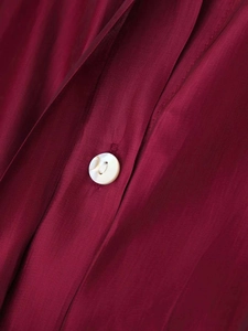 Macro shot of pearl button and wine red silk texture on minimalist fashion shirt