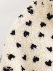 Detailed macro view of soft cream fleece fabric featuring black heart-shaped patterns