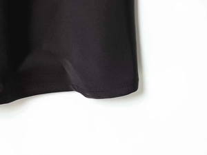 Detailed close-up of neat hem stitching on a black silk-texture satin slip dress