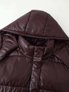 Detailaufnahme einer glänzenden weinroten Winterjacke mit windfester Kapuze und Steppung