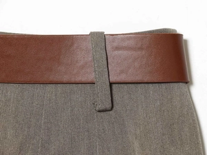 Macro detail of dark brown leather belt on high waisted grey wide leg trousers