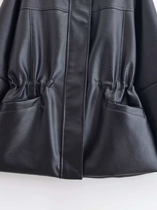 Detail van zwarte leren jas met trekkoord in de taille en een fijne korrelstructuur