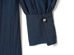 Detail view of navy lantern sleeves with ruffled cuffs and elegant gold metal buttons