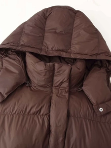 Detailed view of dark brown hooded puffer jacket with high stand collar and metal snaps