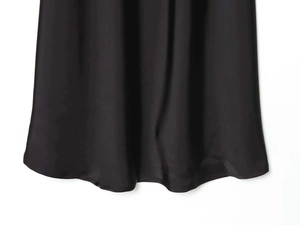 Detail of black satin dress hem showing luxurious smooth texture and elegant drape