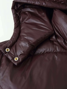 Makro-Detail der glänzend dunkelbraunen Pufferjacke mit hochwertigen Metall-Druckknöpfen