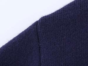 Vue macro d'un tricot violet foncé montrant la texture mohair et la couture d'épaule