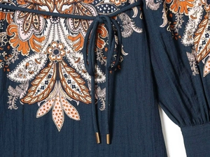 Detailed view of paisley print dress with drawstring waist and gold metal aglets