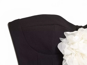 Gros plan détaillé d'une robe bustier noire ornée d'une fleur 3D en résille blanche