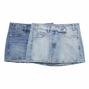 Détail de jupes en jean asymétriques en délavages bleu avec ourlets effilochés