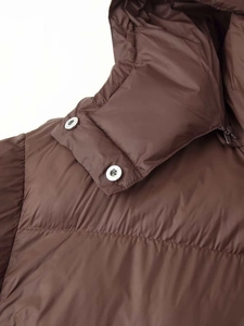 Detail of dark brown hooded jacket collar with silver metal snaps and windproof zipper