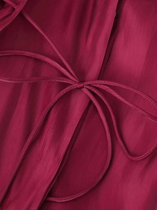 Detail of fuchsia shirt fabric featuring vertical textures and a delicate bow tie knot