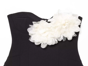 Détail de grandes fleurs 3D en tissu blanc sur une robe d'été noire sans bretelles