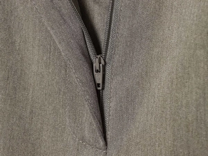 Close-up of olive green wide-leg trousers showing SBC metal zipper and twill fabric
