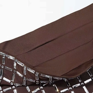 Dettaglio del tessuto marrone scuro con motivo geometrico di cristalli quadrati e tondi