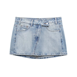 Détail d'une mini-jupe en jean bleu clair avec taille croisée asymétrique et ourlet effiloché