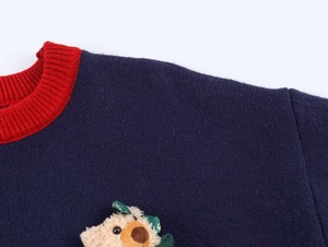 Détail du col rond contrasté et de l'ours 3D sur un pull en maille bleu marine