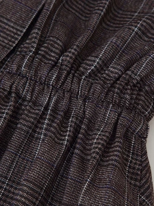 Detail of checkered woven fabric showing smocked elastic waist and plaid texture