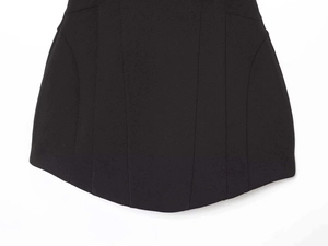 Vue macro détaillée de l'ourlet incurvé et des coutures verticales sur le tissu noir de la robe