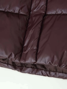 Detail der weinroten, glänzenden Steppjacke mit horizontaler Steppung und warmer Füllung