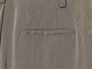 Detailed macro view of olive green wide-leg pants showing the welt pocket and twill fabric
