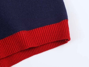 Détail du tricot bleu marine avec poignet côtelé rouge contrasté sur pull d'hiver