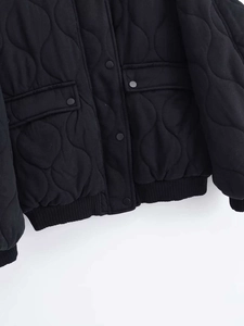 Detail of black onion-quilted jacket featuring metal snap buttons and flap pockets