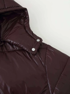 Detailansicht der glänzenden lila Steppjacke mit silbernem Druckknopf am Kragen