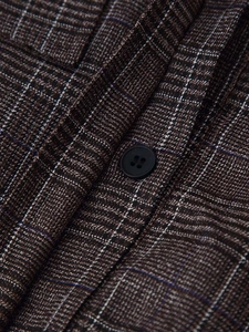 Detail view of deep brown plaid fabric with classic blue-white grid and black round button