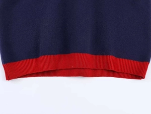 Détail macro du tricot bleu marine et de l'ourlet côtelé rouge sur ce pull élégant