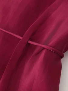 Detailed macro view of the slim waist belt and satin fabric on the magenta fashion shirt