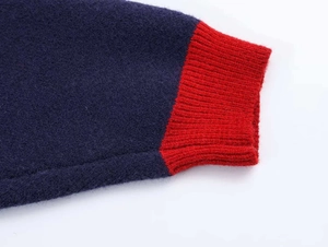 Détail du pull en maille avec corps bleu foncé et poignets contrastés rouges