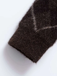 Detail of soft mohair knit cuff with grey V-shaped diamond pattern on dark brown fabric