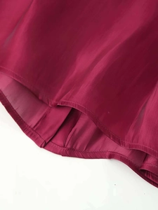 Detailed view of the fine stitching and glossy satin texture on wine red blouse hem