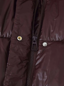 Detail der kastanienbraunen Steppjacke mit Metallreißverschluss und silbernen Druckknöpfen