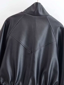 Detail van zwart leren jack met V-vormige stiksels en elastische zoom aan de achterkant