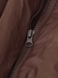 Close-up of durable metal zipper and stitching detail on dark brown winter jacket