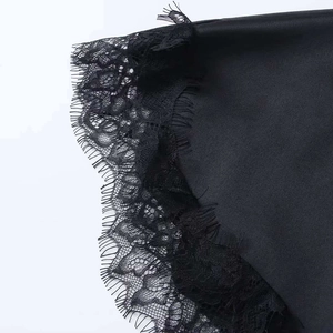 Close-up of black satin fabric with delicate eyelash lace detailing on irregular hemline