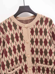 Detail of argyle knit cardigan featuring green and red patterns with gold buttons