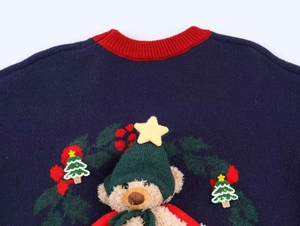 Détail du col en tricot avec un ours en peluche 3D et des broderies festives de Noël