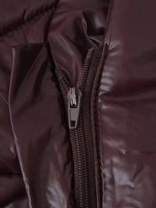 Detailaufnahme aus glänzendem braunem Stoff mit Reißverschluss an einer Pufferjacke