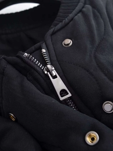 Detail of silver metal zipper and snap buttons on thick black quilted winter jacket
