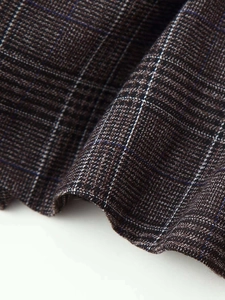 Detail shot of grey and brown plaid woven fabric texture with smooth ruffled hem finish