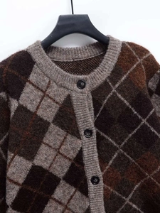 Close-up of the round neckline and argyle knit pattern on the brown cardigan sweater