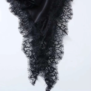 Close-up of black satin dress with intricate floral eyelash lace and asymmetric hem detail