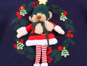 Détail du charm ours 3D et des patchs de sapin sur un pull en maille bleu marine